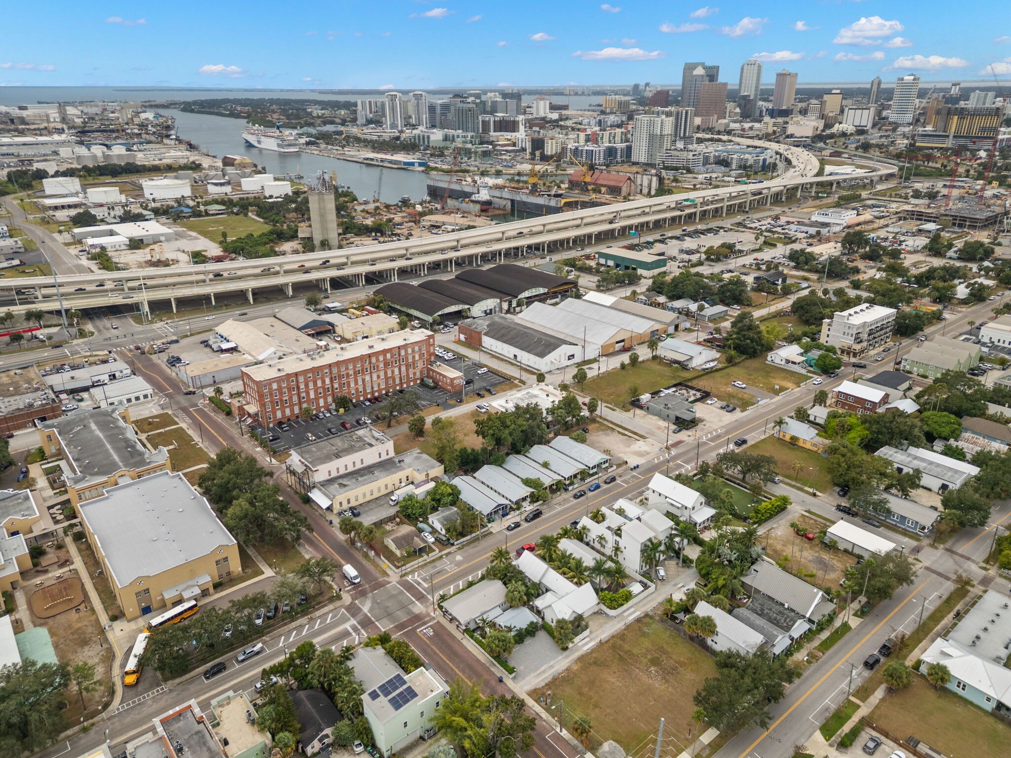 An aerial view of a city with a mix of commercial and residential buildings, a river, and a highway.