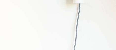 Un luminaire mural doté d’un abat-jour cylindrique et d’un cordon flexible.