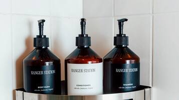 A bathroom shelf with three bottles of Ranger Station body wash, conditioner, and shampoo.