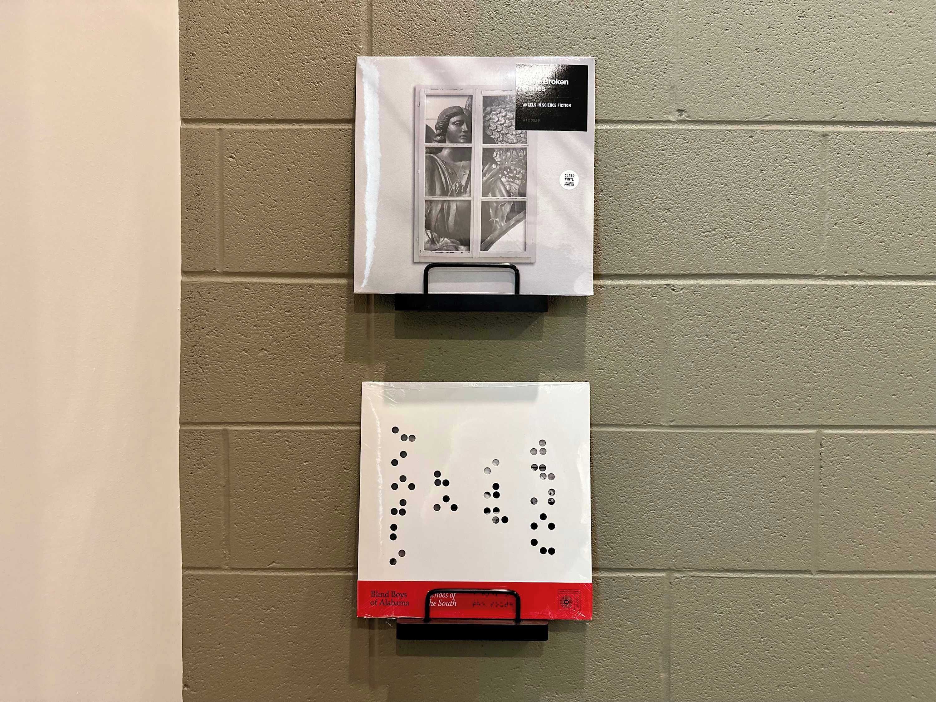 Deux livres sont posés sur un mur, l’un intitulé « Les anges dans la science-fiction » et l’autre « Les jeunes aveugles de l’Alabama ».