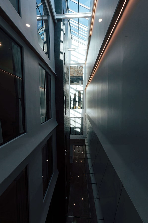A modern building with a glass atrium, large windows, and a narrow corridor.