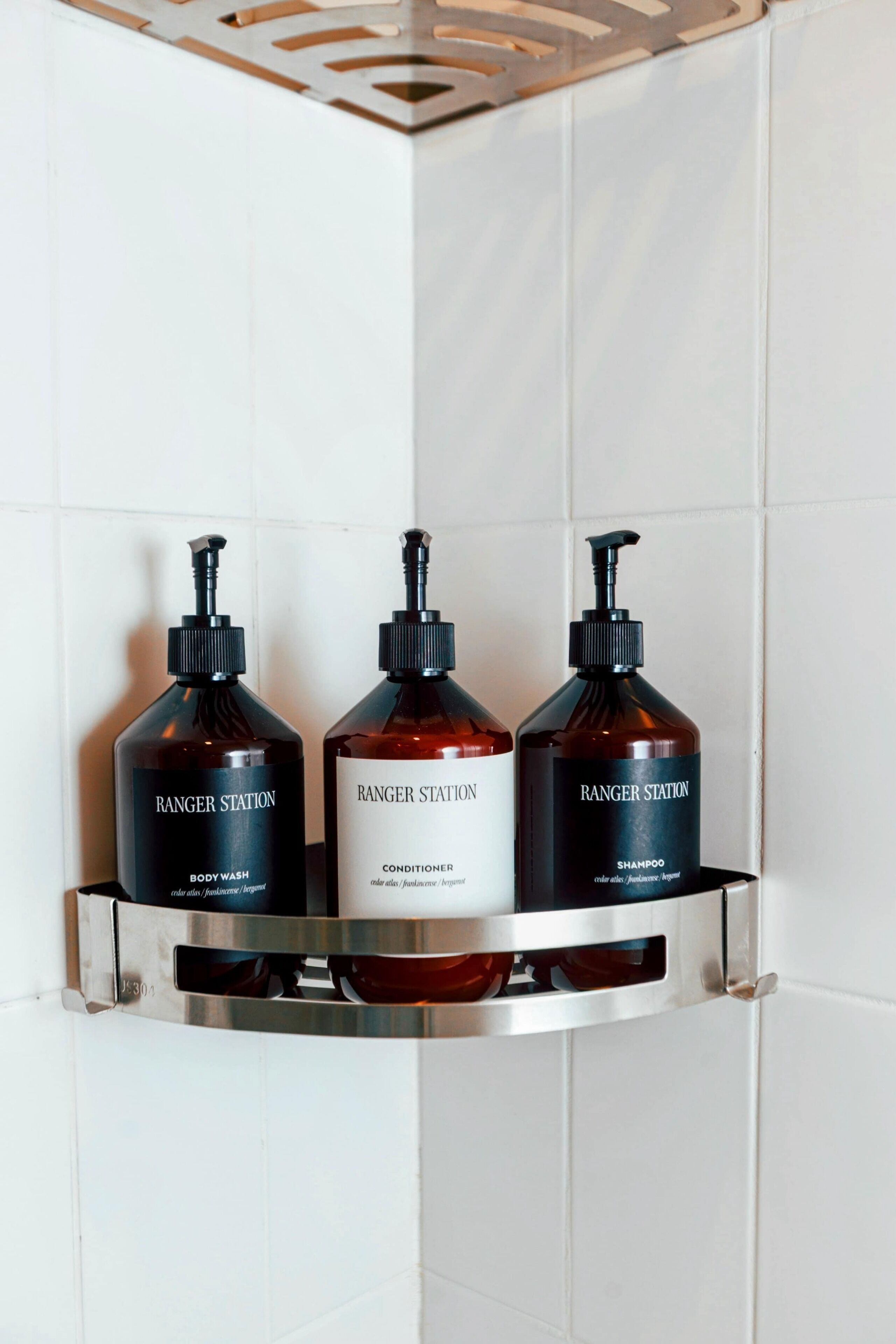 Uma prateleira no banheiro com três frascos de sabonete líquido, condicionador e shampoo Ranger Station.