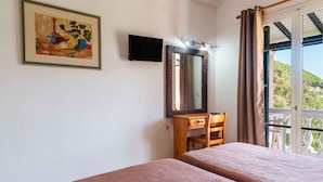 A room with two beds, a wooden desk, a television, and a large mirror. - Pink House Socrates Corfu Beachside Studio (Corfu)