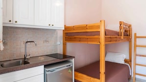 A bunk bed with a wooden frame and a mattress, a kitchen area with a sink and cabinets, and a small refrigerator. - Pink House Socrates Kerkyra Beachside Studio (Corfu)