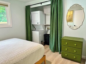 A bedroom with a bed, a green dresser, a washing machine, and a mirror. - Charming 2BR in Columbia Walkable Pet-friendly (Bellingham)