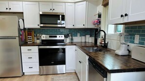 A modern kitchen with white cabinets, stainless steel appliances, a microwave, oven, dishwasher, and a blender. - Charming 2BR in Columbia Walkable Pet-friendly (Bellingham)
