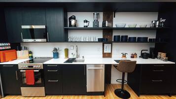 A modern kitchen with black cabinets, a white countertop, and stainless steel appliances.