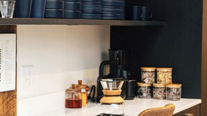 Una cucina moderna con un piano di lavoro bianco, una macchina da caffè e diversi utensili da cucina.