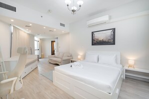 A modern hotel room with a large bed, a desk, a chair, and a sofa. - Stayshort - Serene 2-bedroom With Relaxing Balcony Atmosphere in Liwan (Dubai)