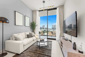 A modern living room with a sofa, coffee table, and a large TV. - Stayshort - Sophisticated JVC Apartment Sleeps 4 With Balcony (Dubai)