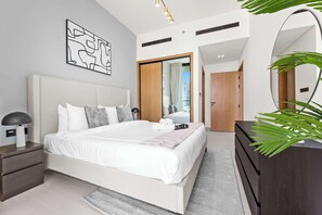 A modern bedroom with a large bed, bedside tables, a wardrobe, and a mirror. - Stayshort - Sophisticated JVC Apartment Sleeps 4 With Balcony (Dubai)