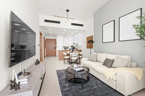 A modern living room with a sofa, coffee table, and a flat-screen TV mounted on the wall. - Stayshort - Sophisticated JVC Apartment Sleeps 4 With Balcony (Dubai)