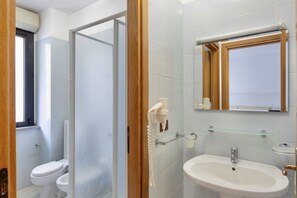Un baño con inodoro, lavabo y cabina de ducha de vidrio.