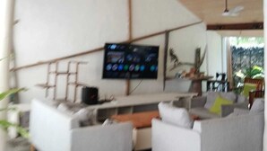 Una sala moderna con una televisión de pantalla plana montada en la pared, dos sofás y ventiladores de techo.