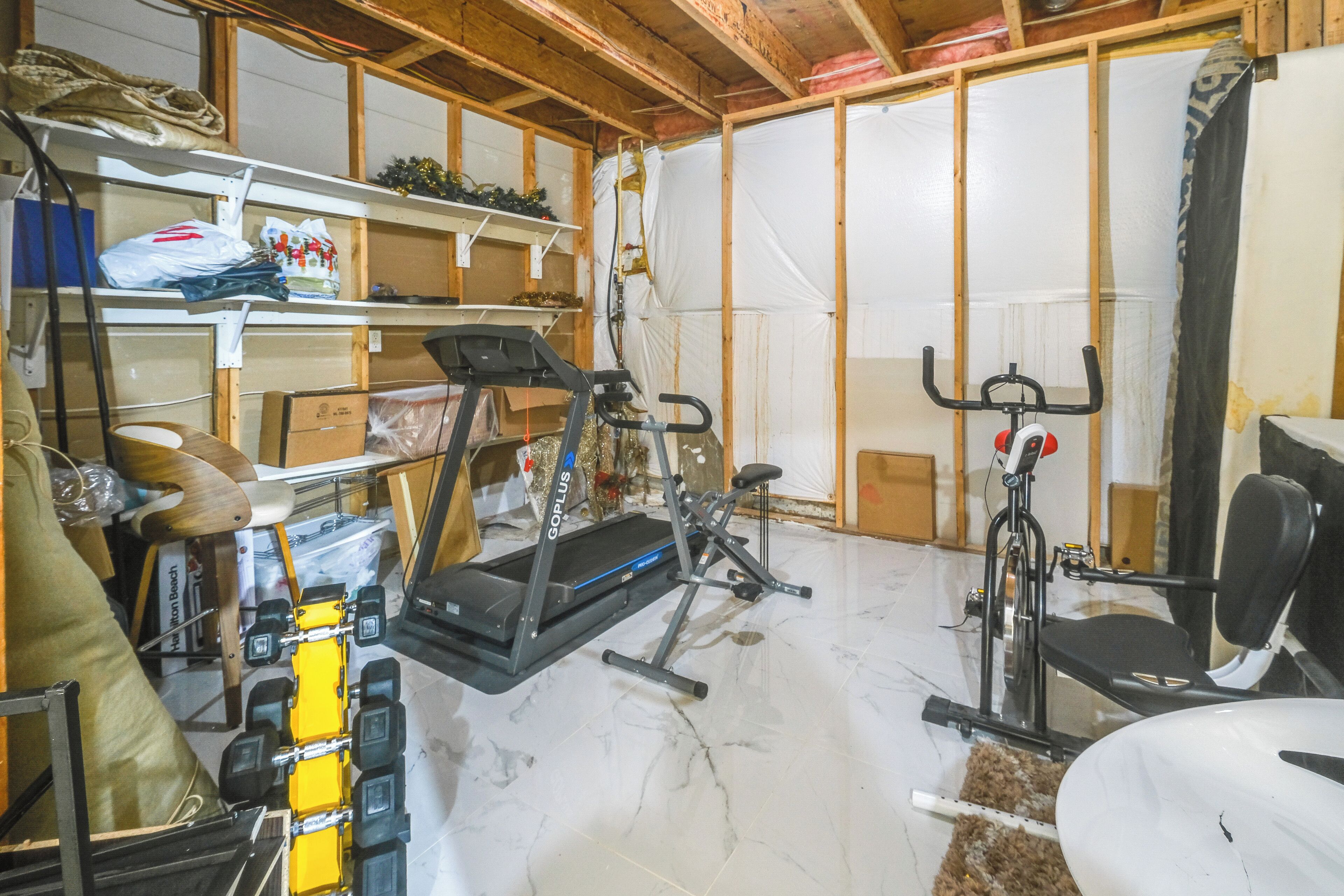 Gimnasio en casa con equipo de ejercicio, incluyendo una cinta de correr, bicicleta estática y pesas.