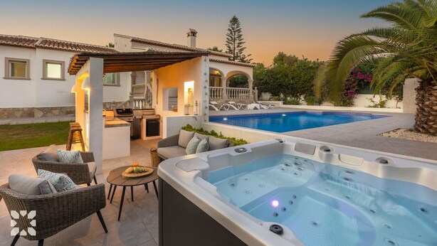 Ein moderner Poolbereich im Freien mit Whirlpool, Liegestühlen und einer überdachten Sitzgelegenheit.