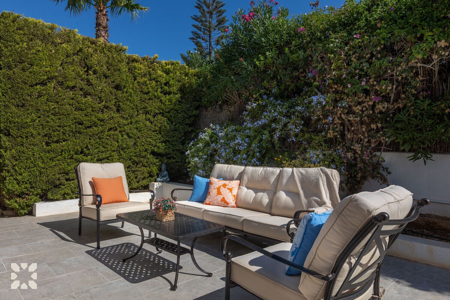 An outdoor seating area with a sofa, two chairs, and a table.