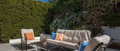 An outdoor seating area with a sofa, two chairs, and a table.
