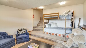 Una habitació amb un llit superposat, una cadira, un taulell amb un joc de taula i un os de peluix.