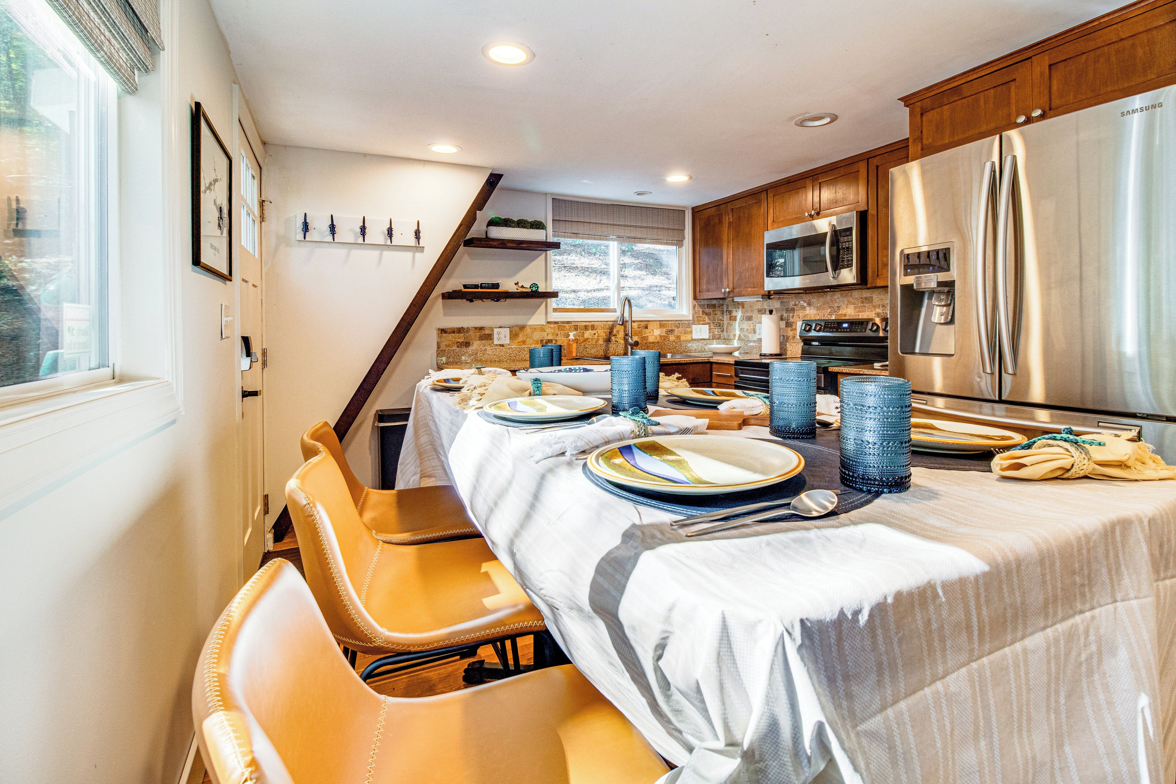 A modern kitchen with wooden cabinets, stainless steel appliances, and a dining area set for six.