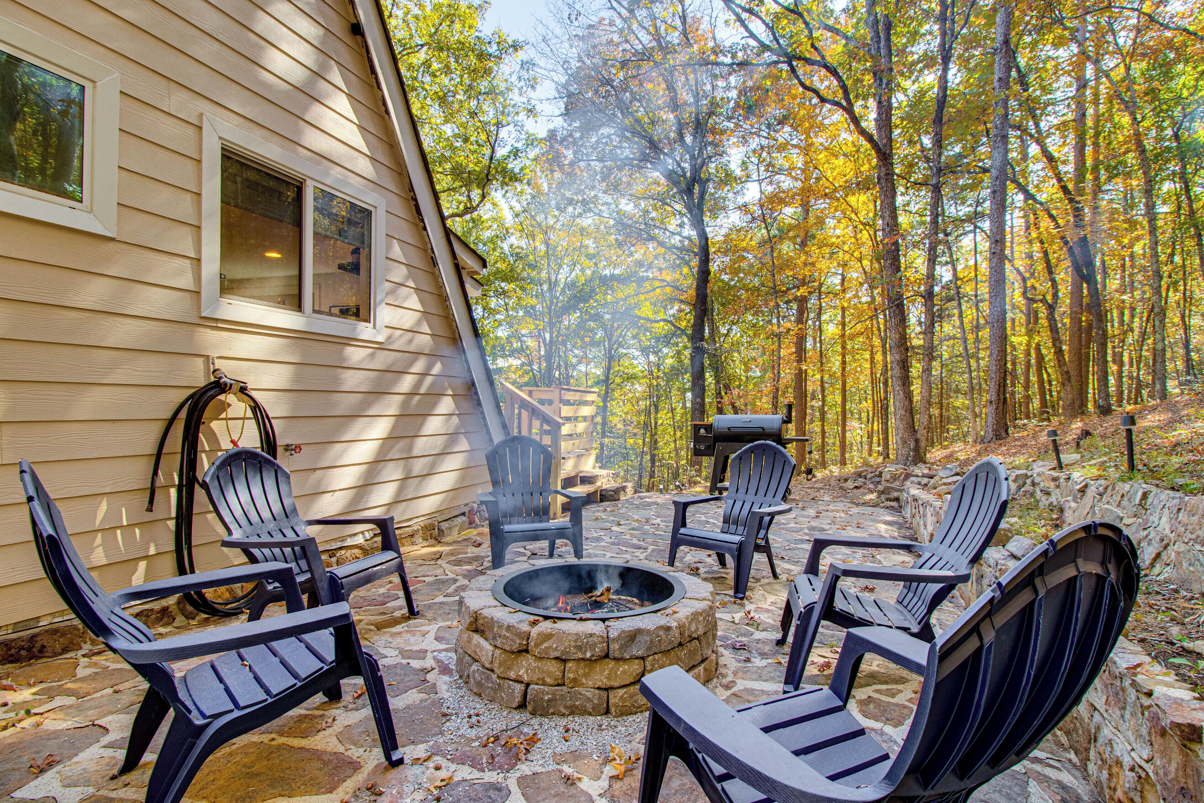 Een terras van natuursteen met Adirondack-stoelen, een vuurkorf en een barbecuehoek.