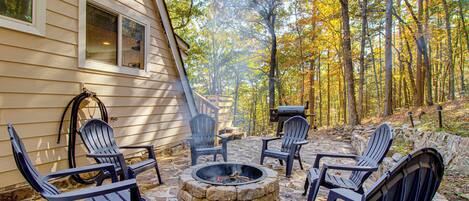 Een terras van natuursteen met Adirondack-stoelen, een vuurkorf en een barbecuehoek.