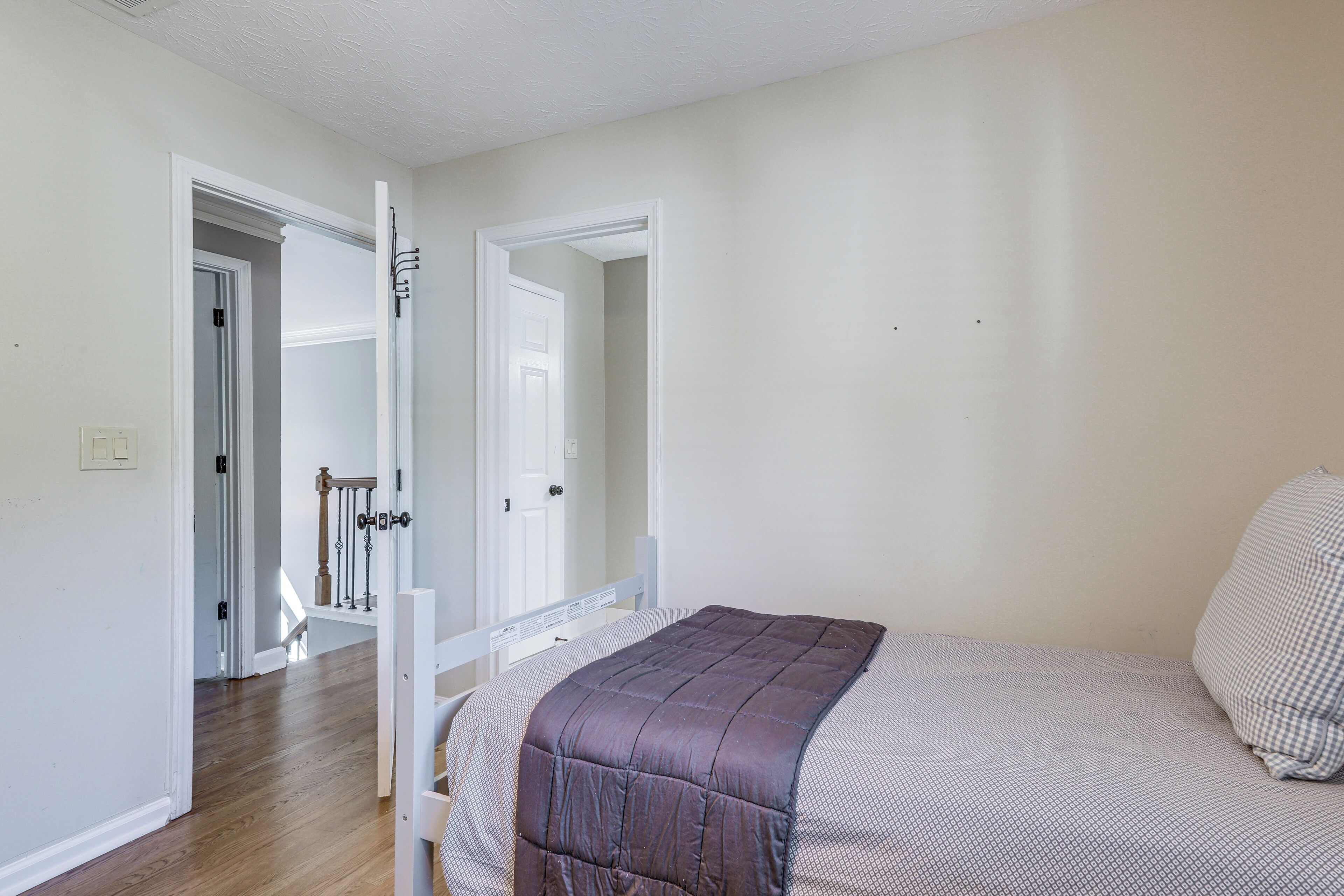 Une chambre à coucher avec un lit, une porte donnant sur un couloir et un escalier.