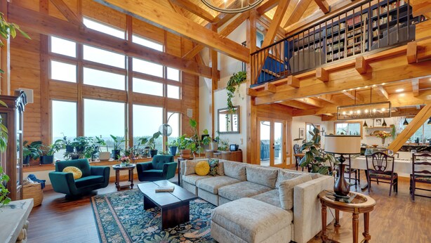 A spacious living area with a large sectional sofa, a coffee table, and a rug. There is a staircase leading to an upper level with bookshelves. - Big Groups Welcome! Mtn-view Onalaska Estate (Onalaska)