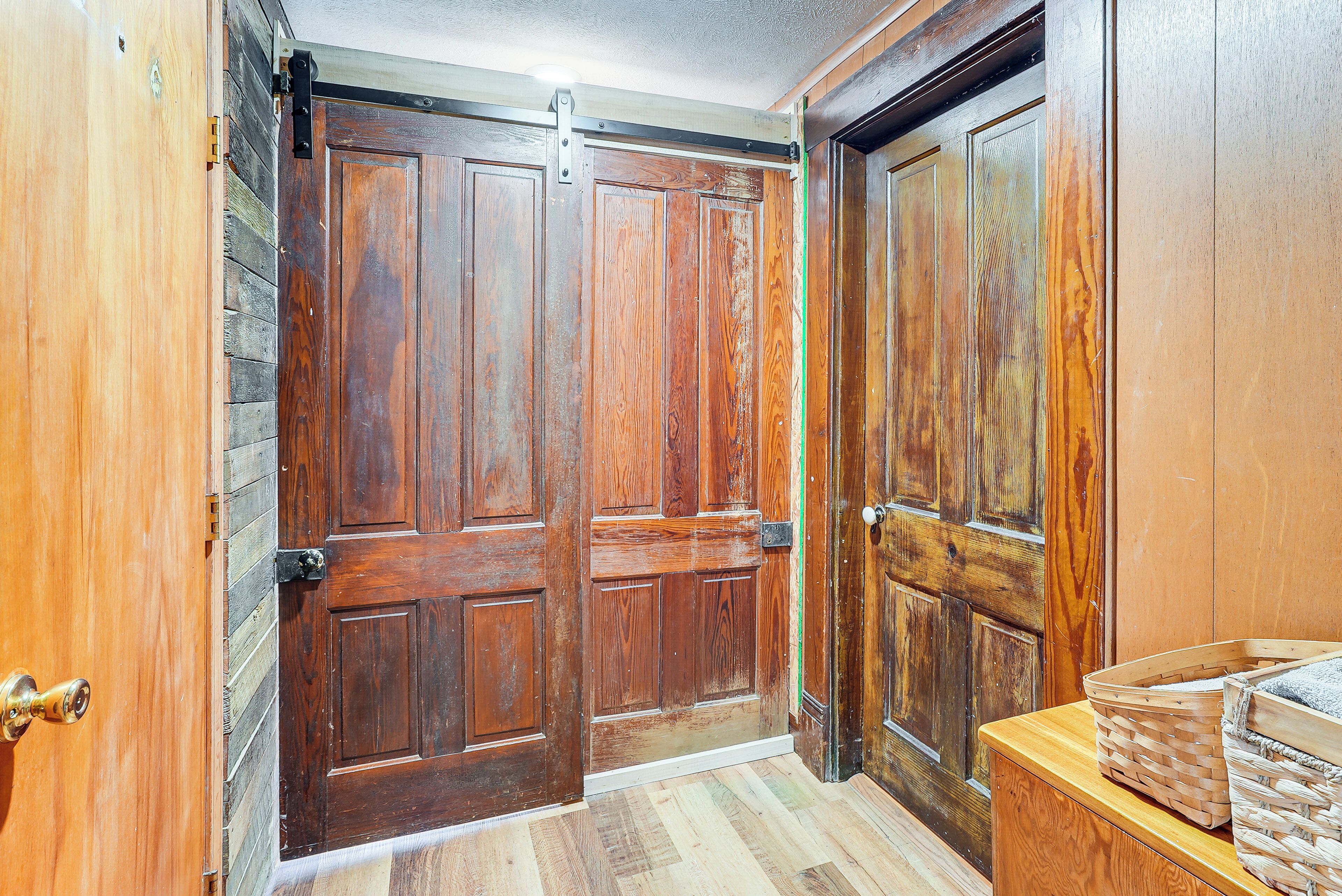 A wooden door with a sliding mechanism, a wooden wall, and a wooden bench with baskets. - Pet-friendly Home w/ River Access in Crothersville (Crothersville)