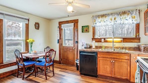 A kitchen with wooden cabinets, a dishwasher, a dining table with chairs, and a window with blinds. - Pet-friendly Home w/ River Access in Crothersville (Crothersville)