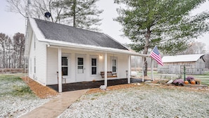 A white single-story house with a porch, a flag, and a barn in the background. - Pet-friendly Home w/ River Access in Crothersville (Crothersville)