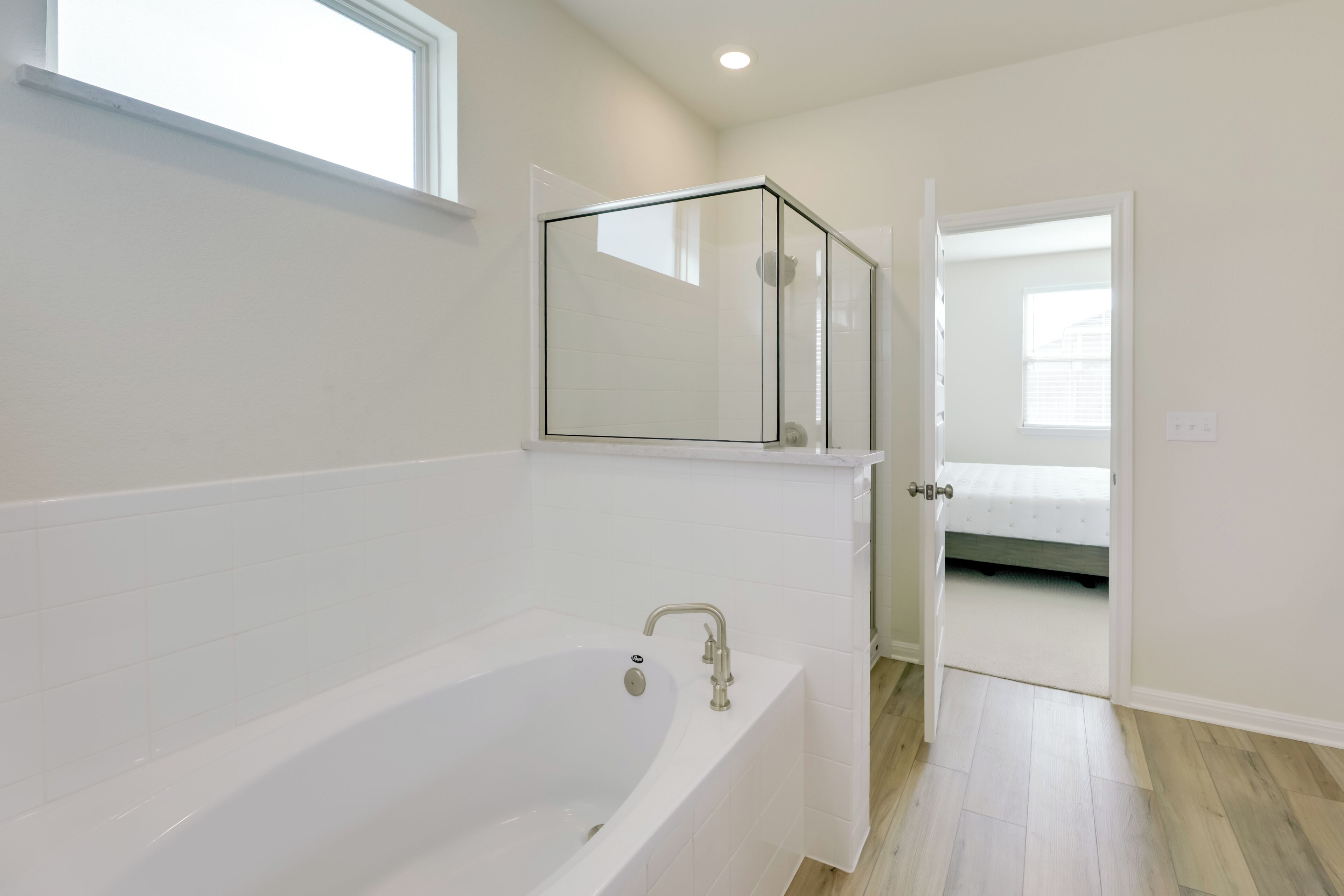 Une salle de bain moderne dotée d’une grande baignoire, d’une cabine de douche en verre et d’une porte donnant sur une chambre.