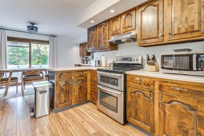 A kitchen with wooden cabinets, stainless steel appliances, and a view of the outdoors.