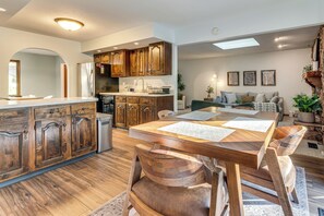 A spacious kitchen with wooden cabinets, a dining area with a wooden table and chairs, and a living room with a sofa and decorative items.