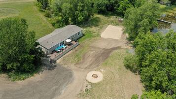 An aerial view of a house with a patio, a swimming pool, and a large yard.