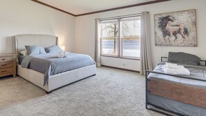 Ein Schlafzimmer mit Bett, Nachttisch, Fenster mit Blick und einem Bild an der Wand.