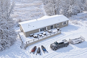 A house with a covered patio, a truck, and three snowmobiles parked in front. - Snowmobile, Fish & Relax: Mink Lake Retreat (Buffalo)