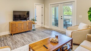 A living room with a wooden entertainment center, a television, a coffee table with decorative items, and a sofa. - Family Getaway in Calabash w/ Pool; 9 Mi to Beach (Calabash)