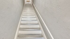 Una escalera con paredes blancas y escalones de madera.