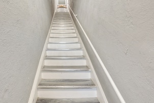 Una escalera con paredes blancas y escalones de madera.