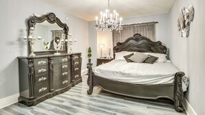 Un dormitorio con una cama grande, un aparador de madera oscura y una araña.