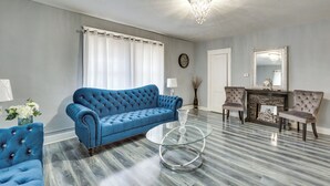 A living room with a blue sofa, two armchairs, a glass coffee table, and a fireplace. - Spacious Condo 4 Mi to Pro Football Hall of Fame! (Canton)