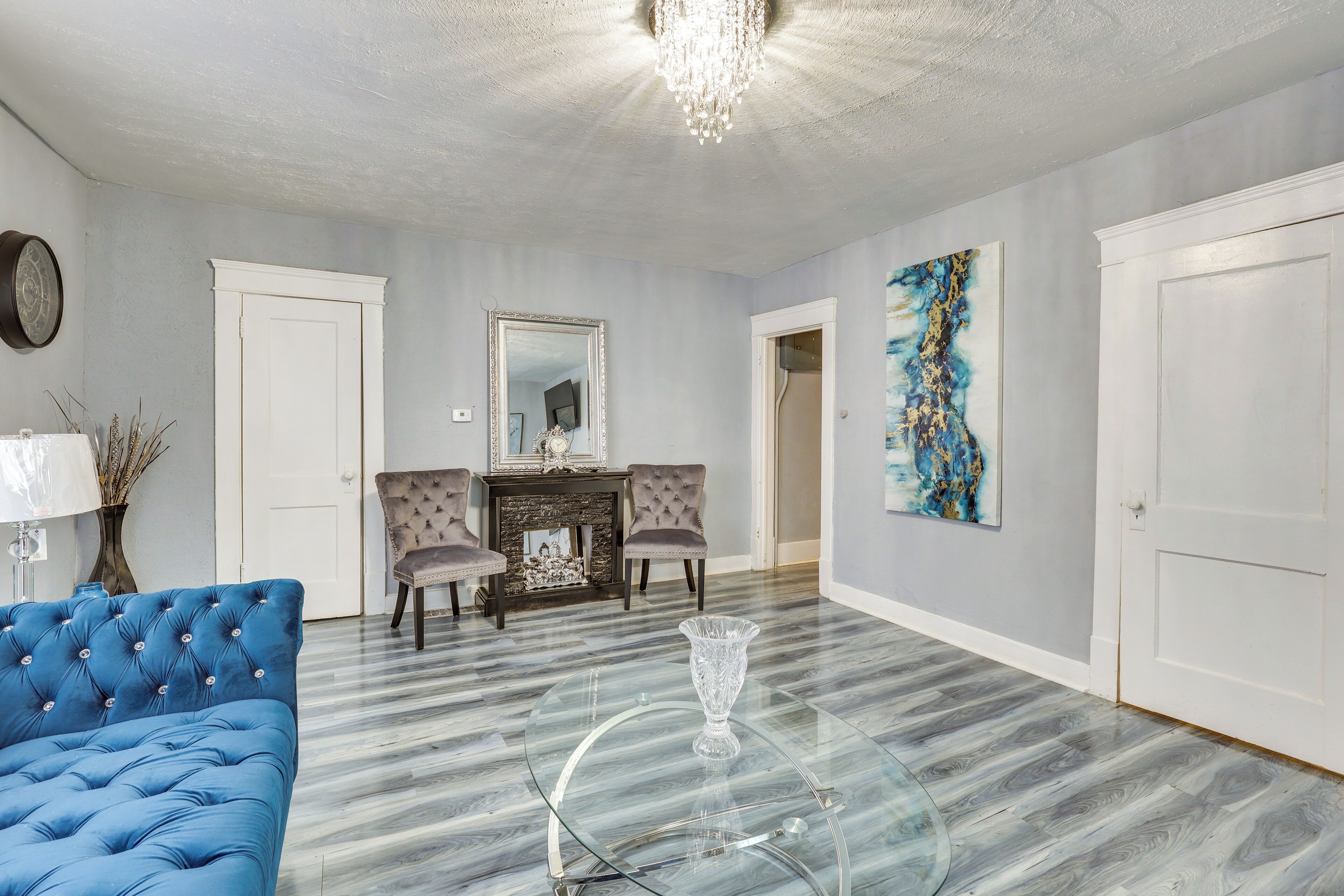 Un salon spacieux avec un canapé bleu, une table basse en verre et une cheminée.