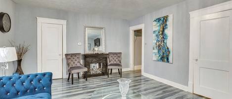 Un salon spacieux avec un canapé bleu, une table basse en verre et une cheminée.