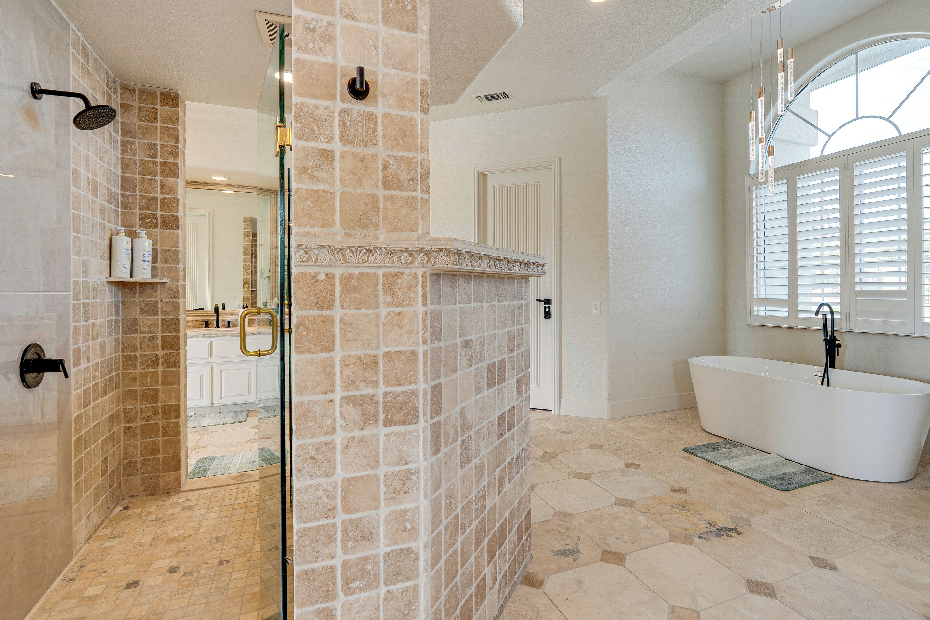 A bathroom with a shower, a bathtub, and a large window.
