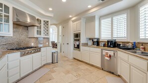 A modern kitchen with white cabinetry, granite countertops, stainless steel appliances, and a built-in microwave. - Luxury Pilot Hill Estate in a Vineyard Community (Pilot Hill)
