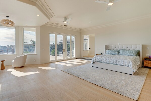 A spacious bedroom with a large bed, a modern chair, and a view through the glass doors. - Luxury Pilot Hill Estate in a Vineyard Community (Pilot Hill)