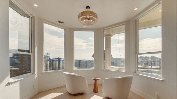 A spacious room with large windows, a modern chandelier, and two white armchairs. - Luxury Pilot Hill Estate in a Vineyard Community (Pilot Hill)