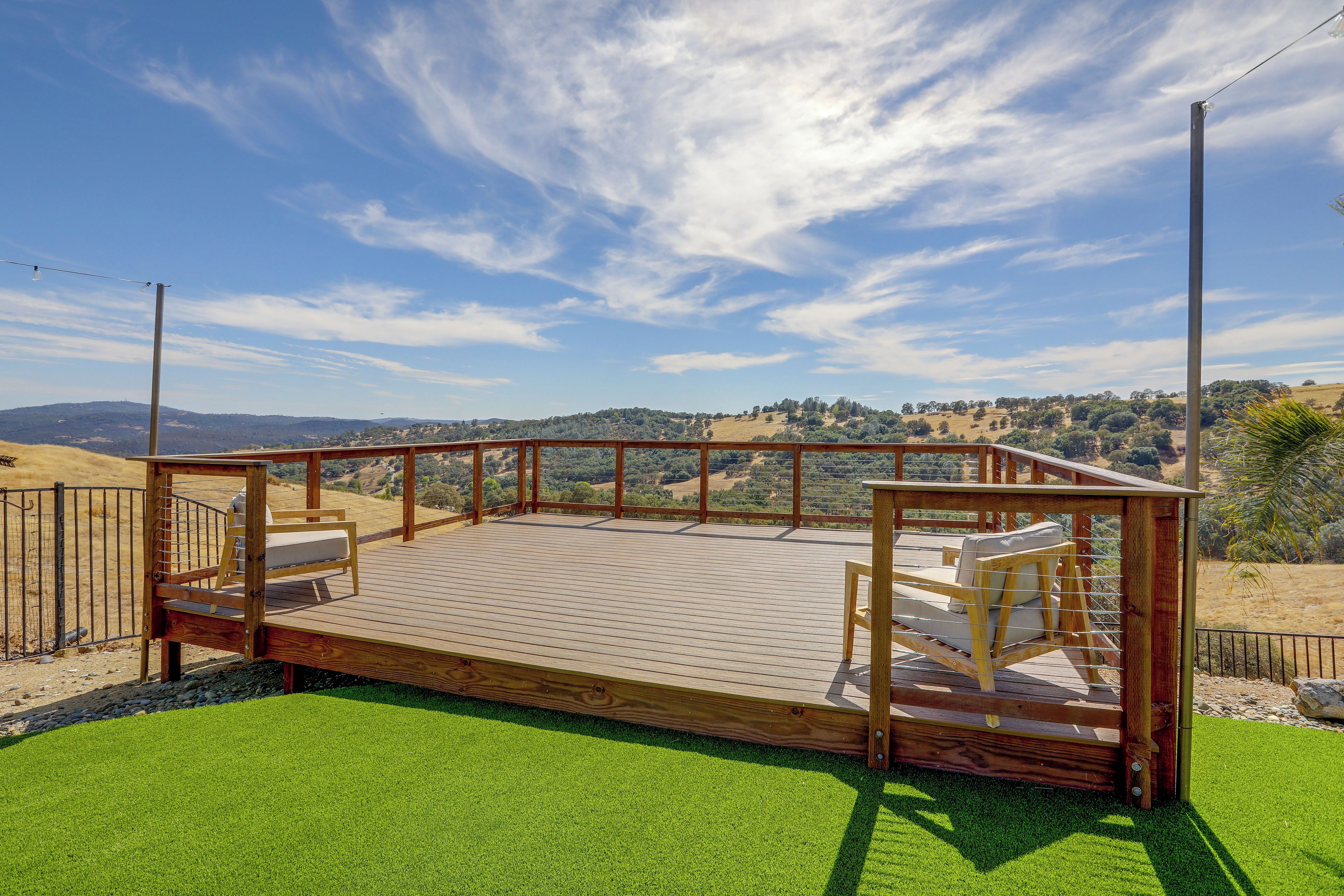 Une terrasse en bois offrant une vue sur un paysage vallonné.
