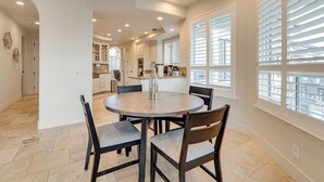 A dining area with a round table, four chairs, and a kitchen in the background. - Luxury Pilot Hill Estate in a Vineyard Community (Pilot Hill)
